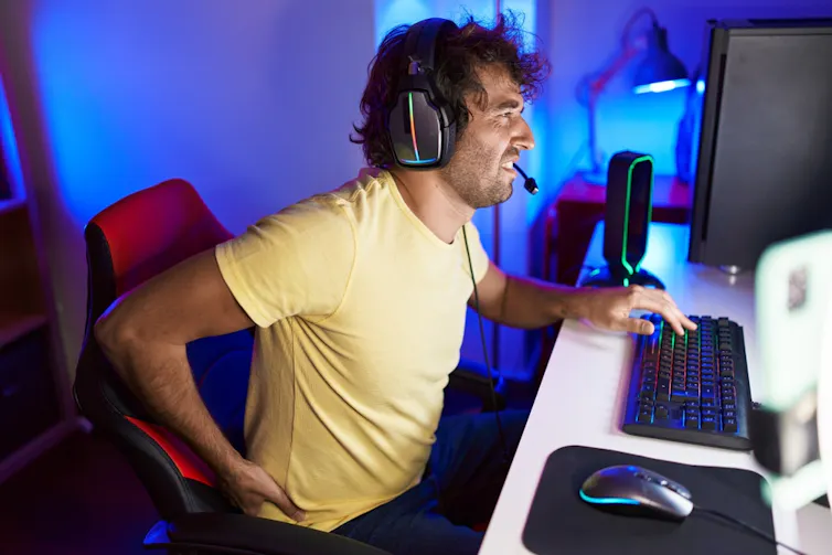 Young man at a computer experiencing lower back pain