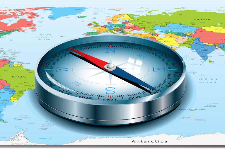 A compass placed on a world map with its needle directed toward the U.S.