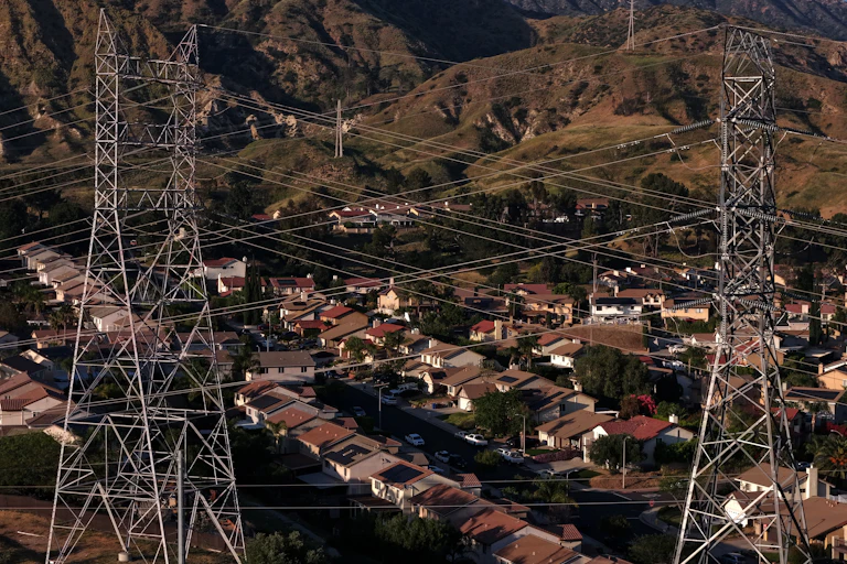 Transmission towers and power lines above a hillside neighborhood