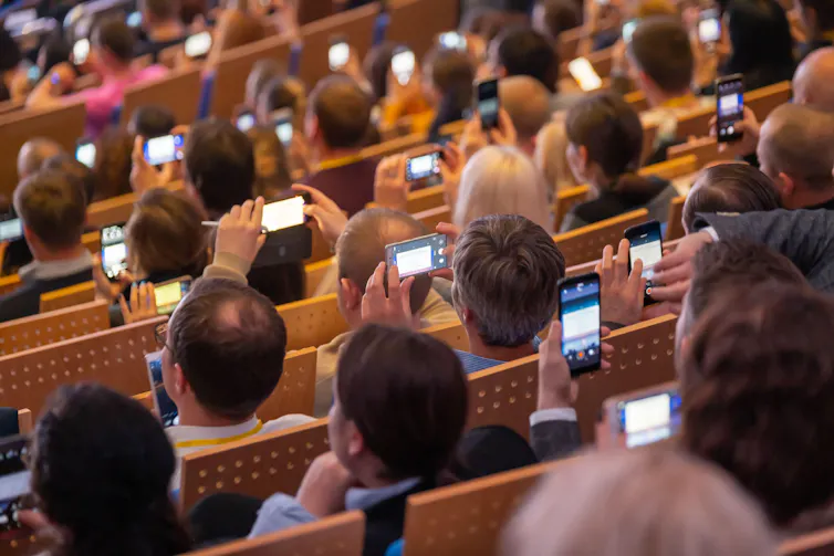 Students in a lecture theatre on their phones