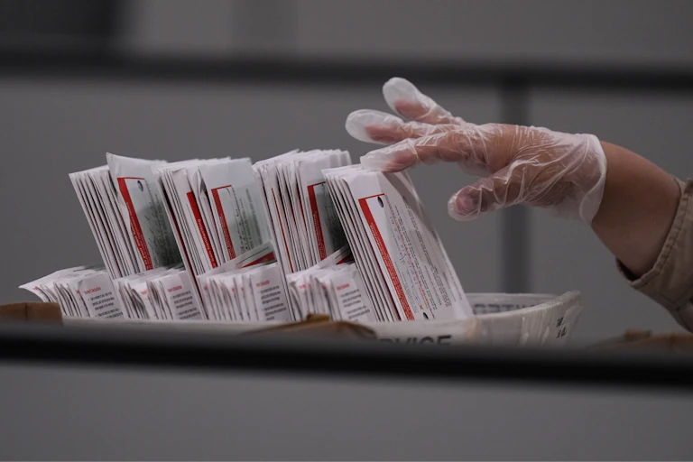 A gloved hand inspects a ballot
