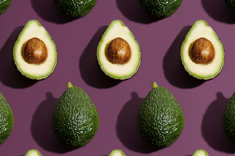 Rows of avocados sliced open showing the seed.