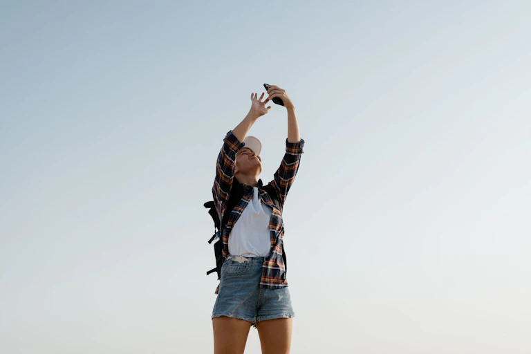 A woman holding her phone to the sky, searching for signal.