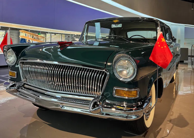 vintage chinese car in a museum with red flags on it.