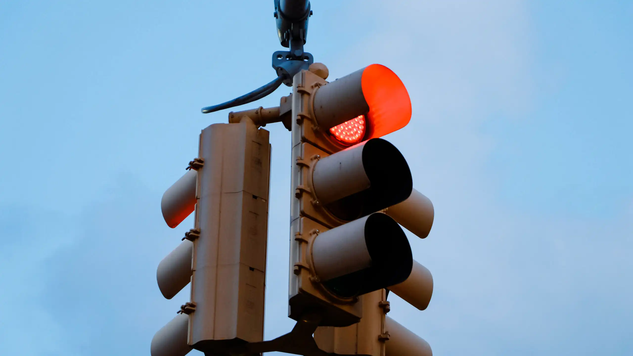 A set of traffic lights against a blue sky.
