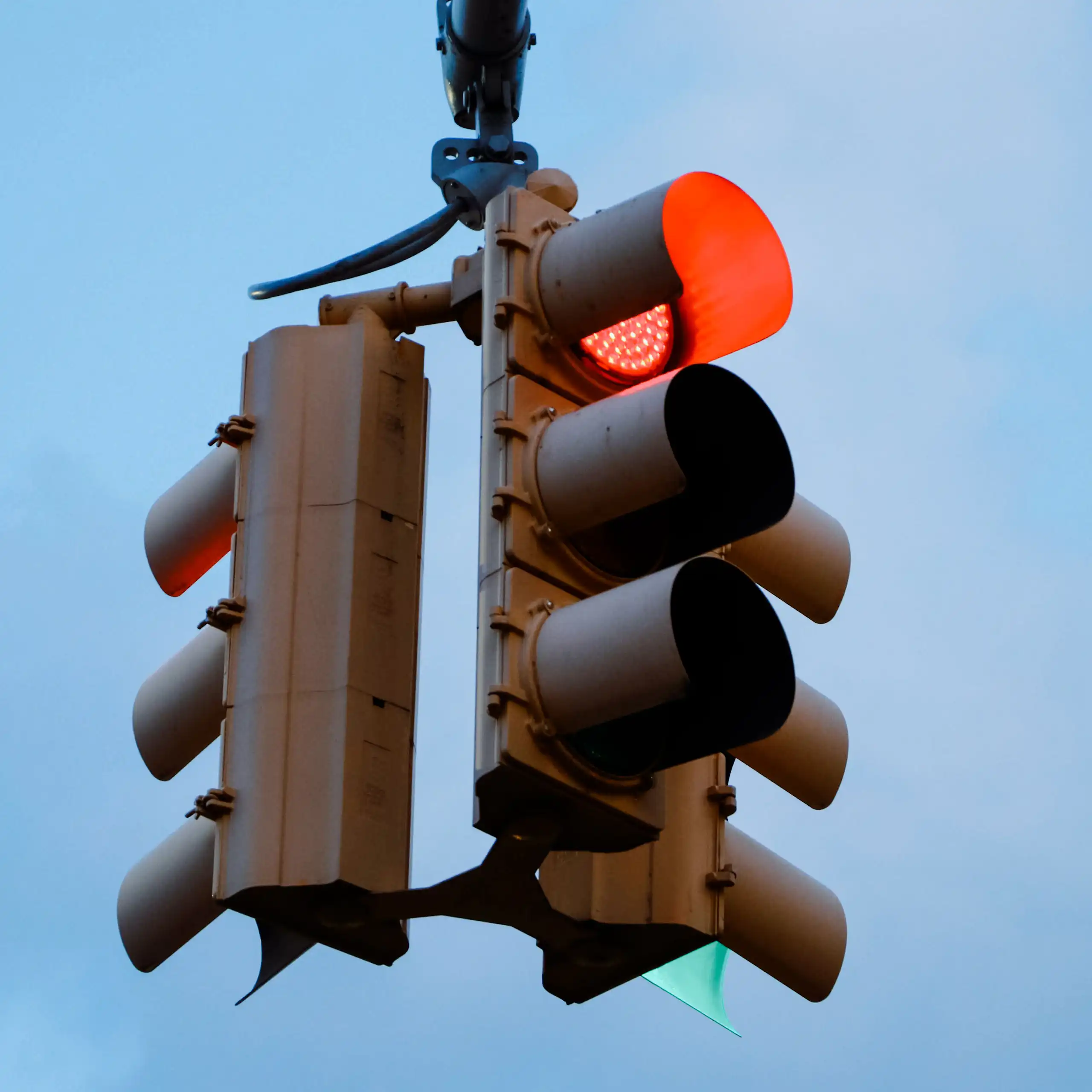 A set of traffic lights against a blue sky.