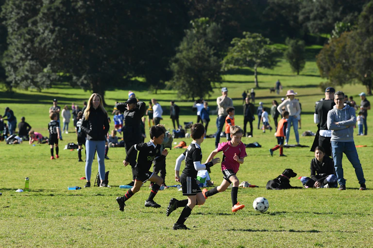 Parents and spectators watch as junior soccer players compete.