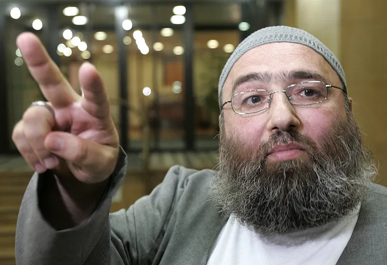 a man in Islamic dress with two fingers raised
