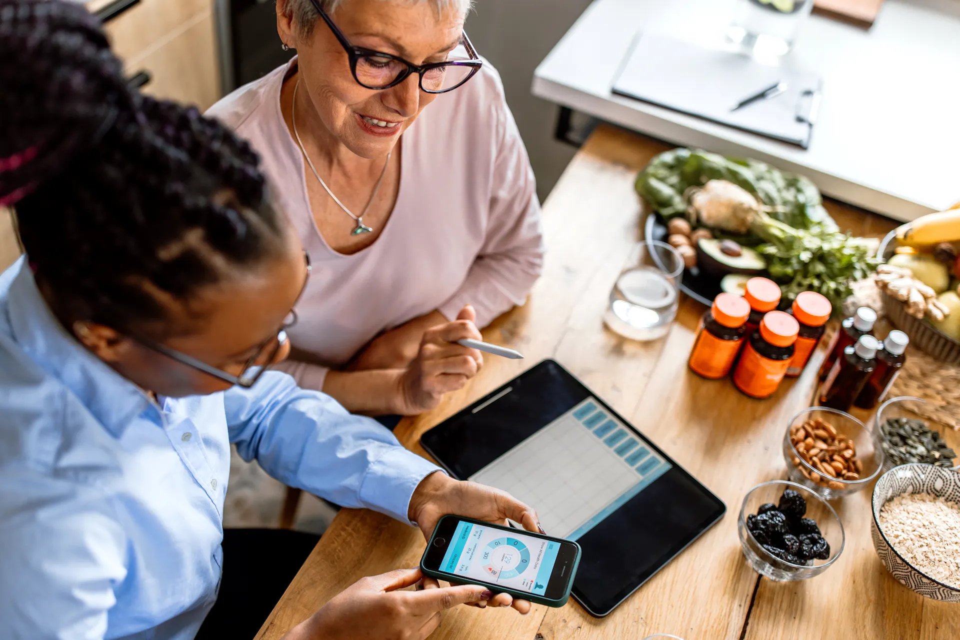A dietician shows an older woman how to track food intake on a smartphone