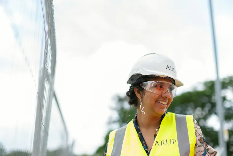 a woman wearing a high-visibility vest, hard hat and protective glasses