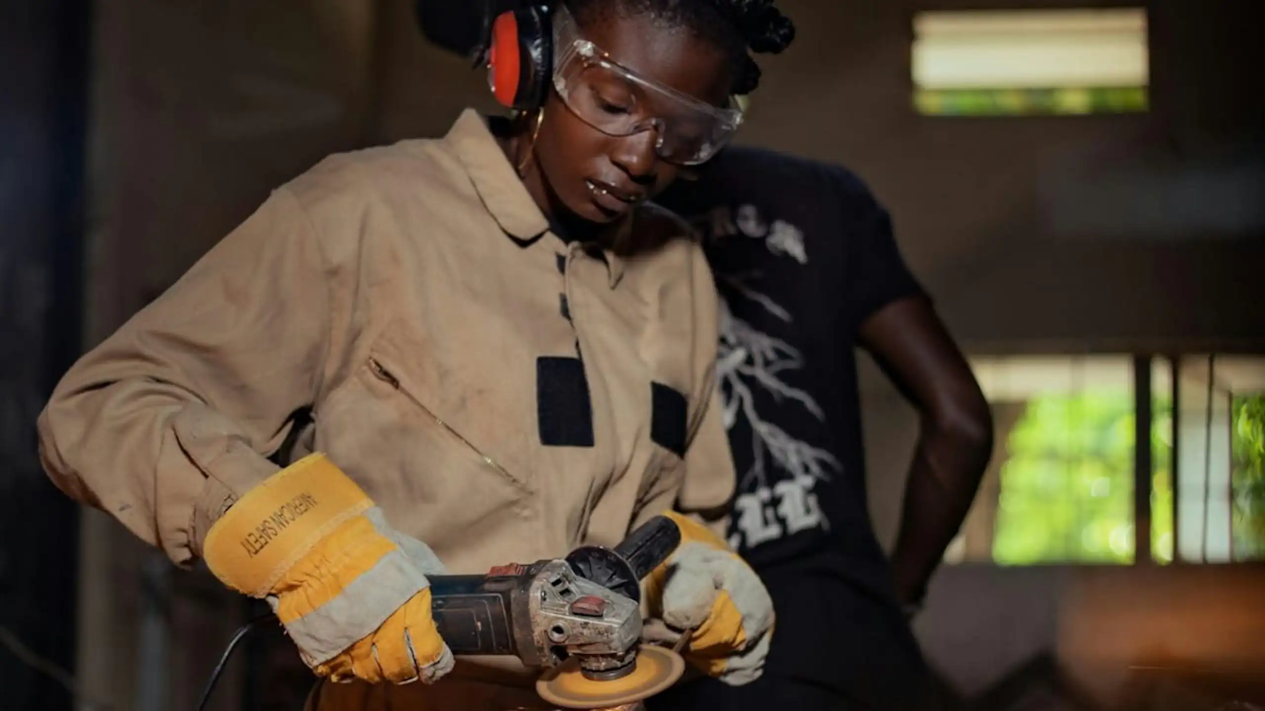 Une personne portant des lunettes de protection, des gants et une combinaison, utilisant un outil électrique