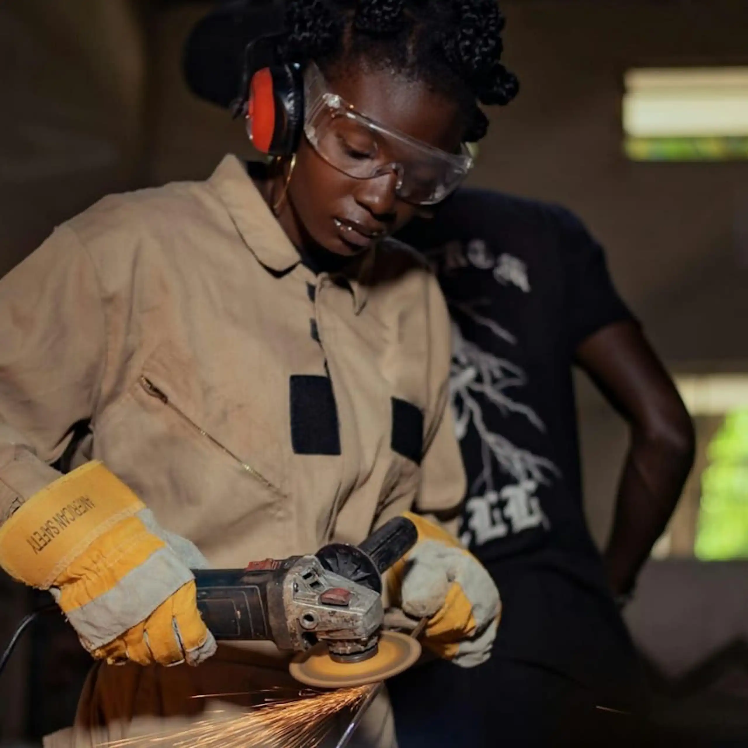 Une personne portant des lunettes de protection, des gants et une combinaison, utilisant un outil électrique