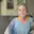 A older woman with a scarf on her head sitting on a couch.