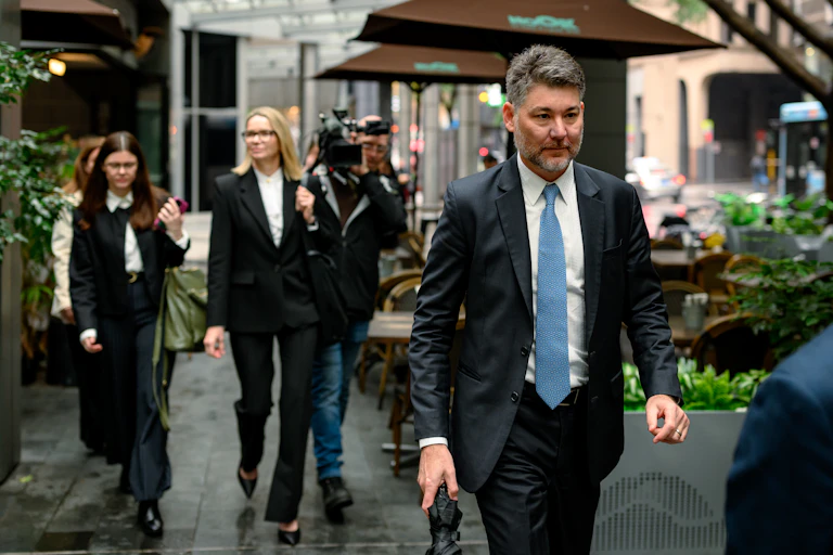 A man in a suit walks outside in a city on a rainy day