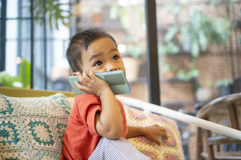 Little boy holds phone to his cheek.
