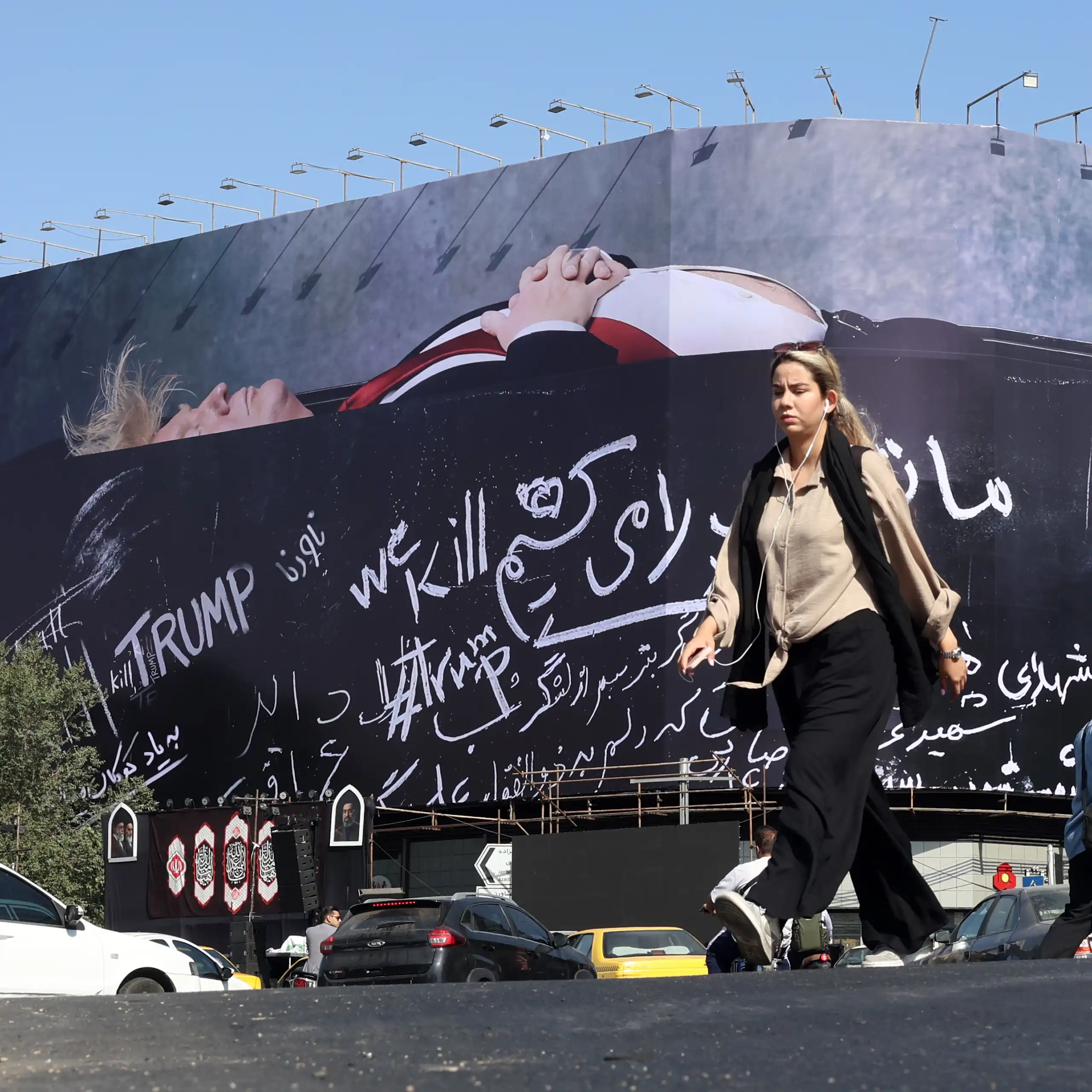 An Iranian woman walks next to a billboard in Tehran featuring Donald Trump in a coffin.