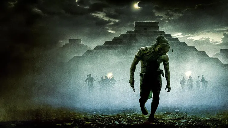 Imagen de la silueta de un hombre caminando delante de un templo maya parcialmente oscurecido.