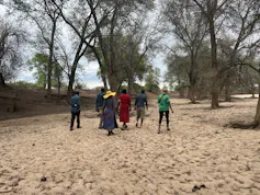 A group of people photographed from the back walking along a dry area