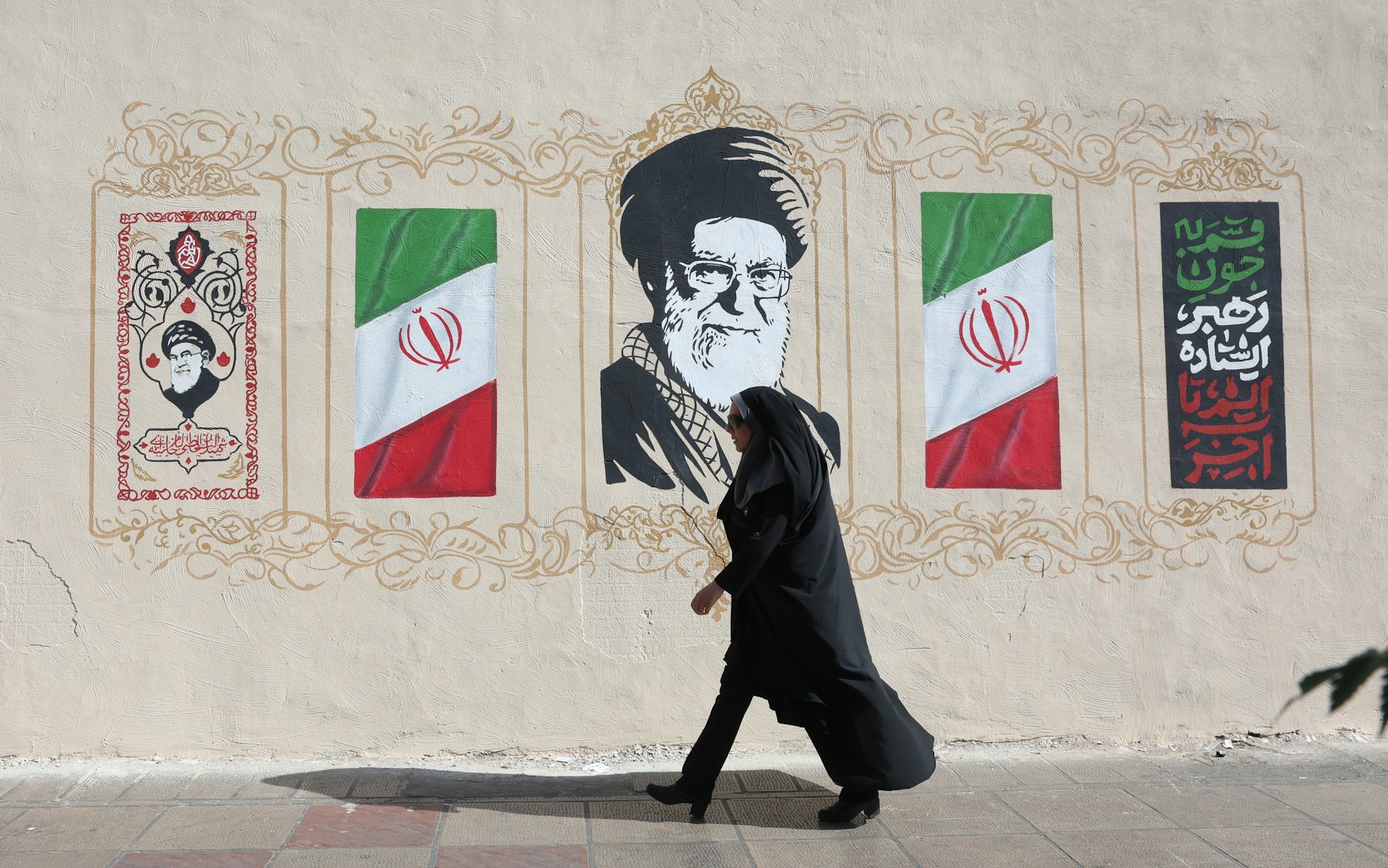 A woman walks past a mural of Iran's late former supreme leader, Ali Khamenei.
