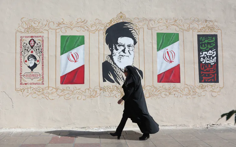 A woman walks past a mural of Iran's late former supreme leader, Ali Khamenei.