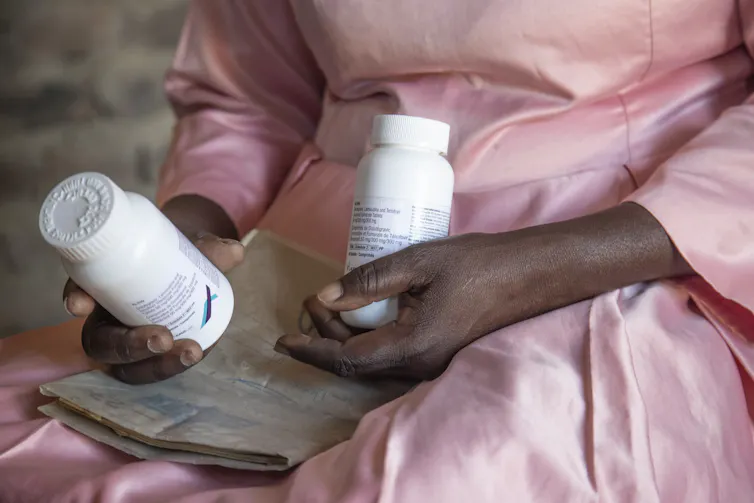 Por qué el último golpe al VIH/SIDA debería hacer sonar la alarma en la respuesta de las Naciones Unidas 1 Las manos negras sostienen un frasco de medicina