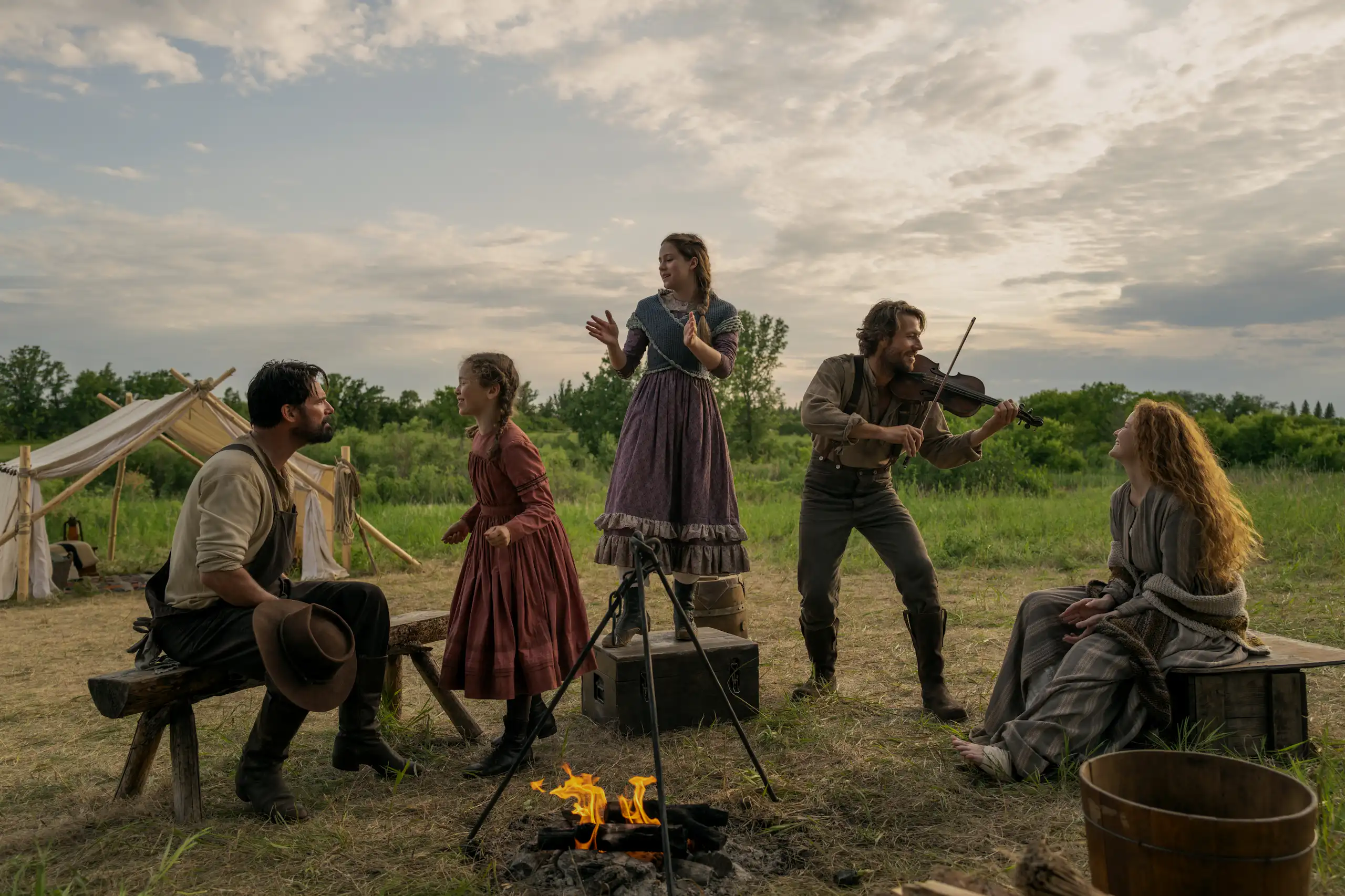 Warren Christie (John Edwards), Alice Halsey (Laura Ingalls), Skywalker Hughes (Mary Ingalls), Luke Bracey (Charles Ingalls) et Crosby Fitzgerald (Caroline Ingalls), autour d'un feu de camp.