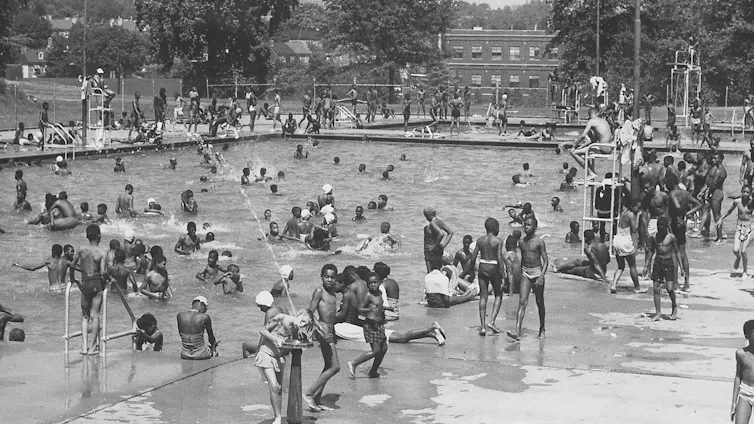 Black and white photo of dozens of Black children in a large swimming pool