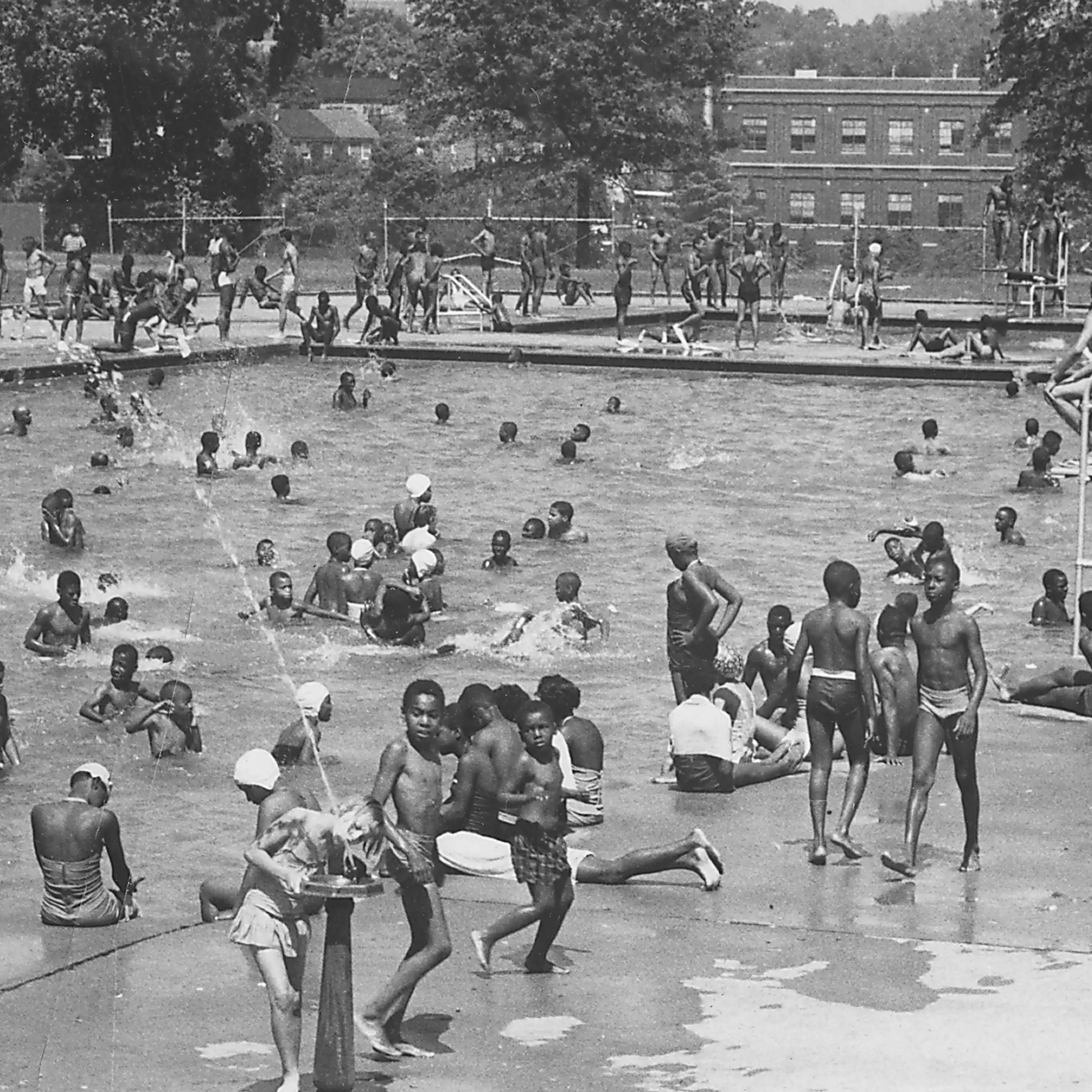 Black and white photo of dozens of Black children in a large swimming pool
