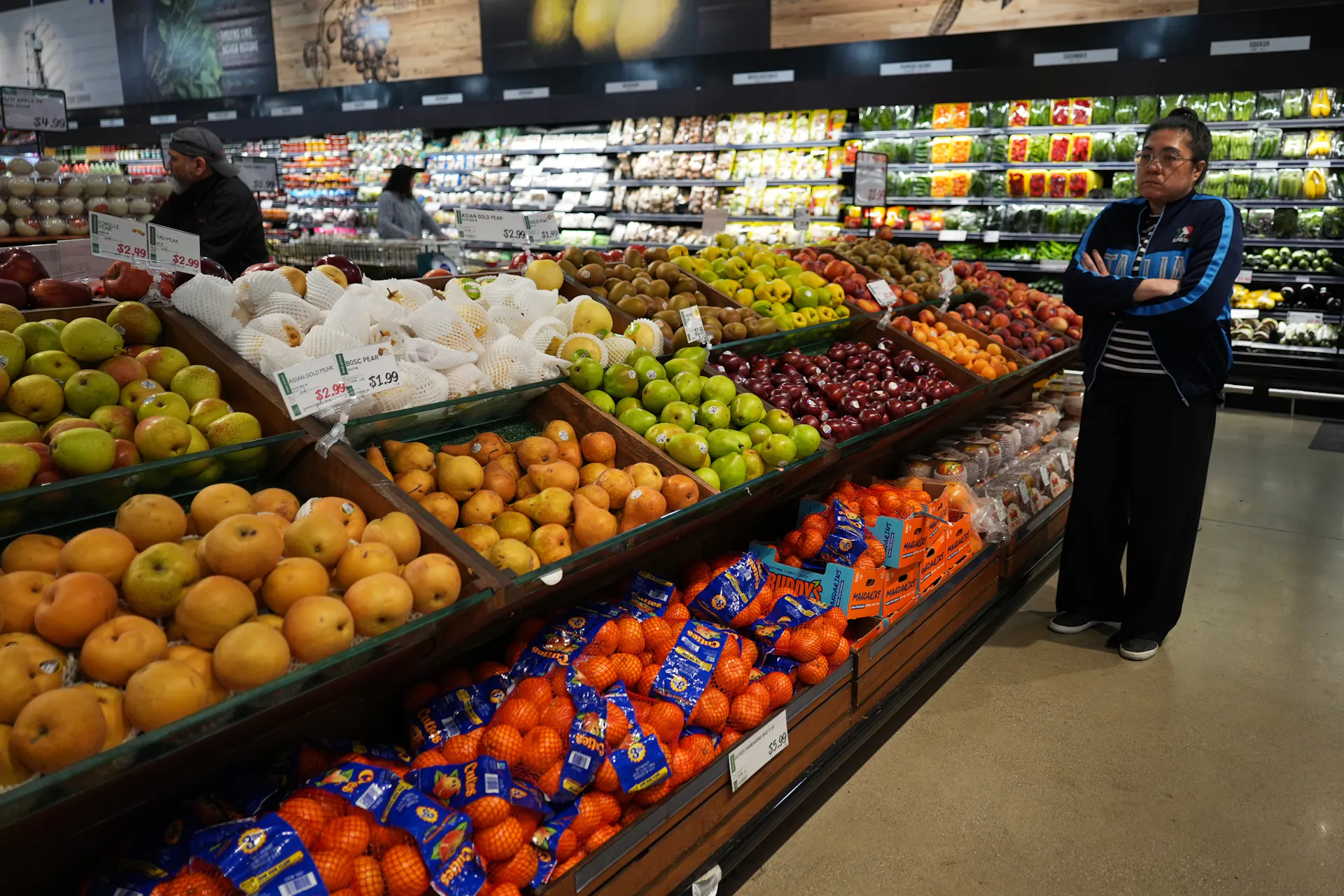 Shoppers inspect the offerings in the produce aisle, including apples, plums and pears, at a grocery store in Schaumburg, Ill.