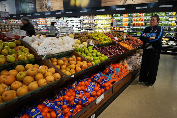 Shoppers inspect the offerings in the produce aisle, including apples, plums and pears, at a grocery store in Schaumburg, Ill.