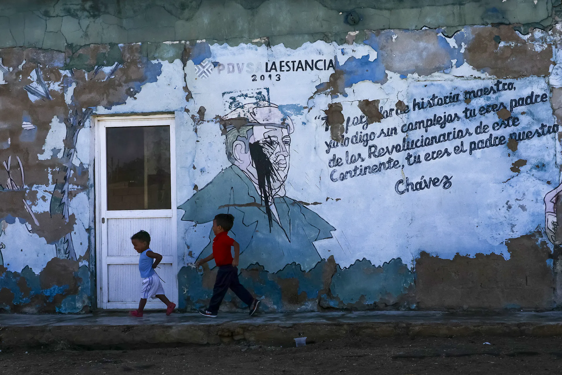 Two boys walk outside a broken-down building.