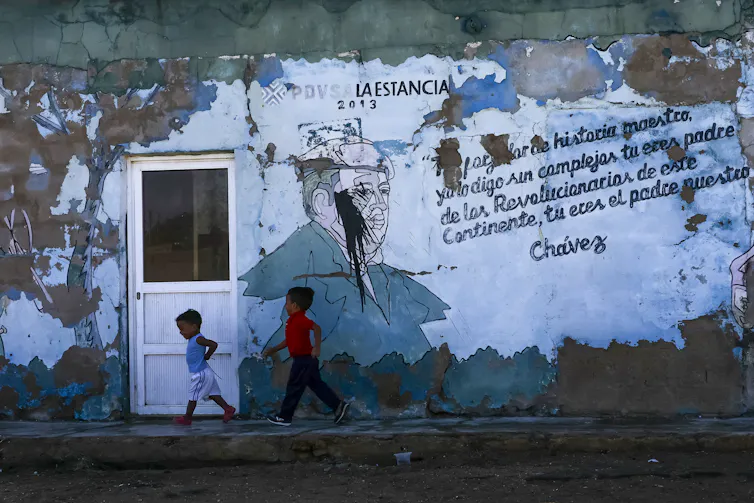 Two boys walk outside a broken-down building.