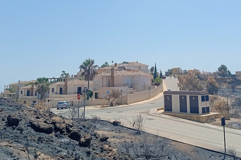 Casas de un pequeño pueblo rodeado por un paisaje calcinado tras un incendio
