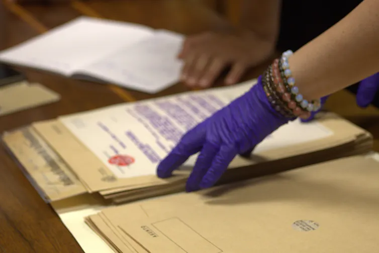 Una mano enguantada muestra varios documentos.