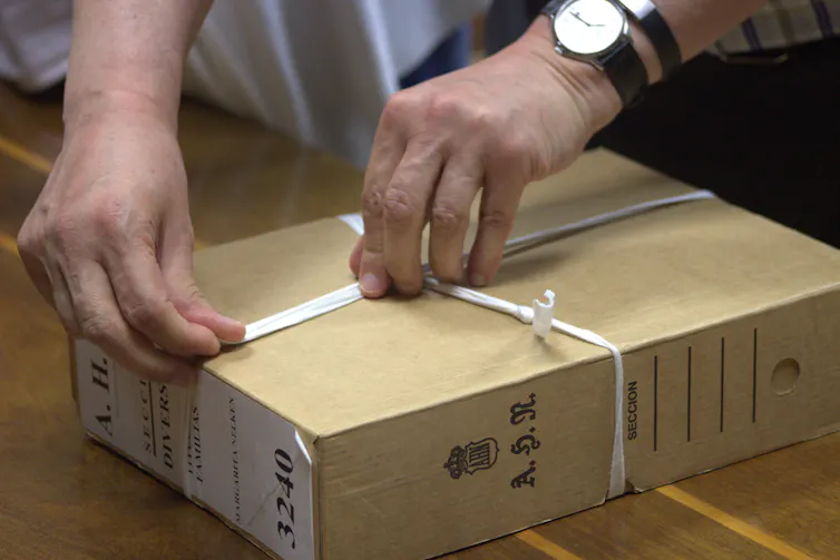 Cartas desde el exilio: Azan ante un papel en blanco 1 Imagen de manos abriendo la cinta que rodea la caja.