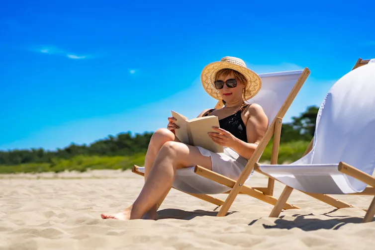 A woman reading a book on a beach.