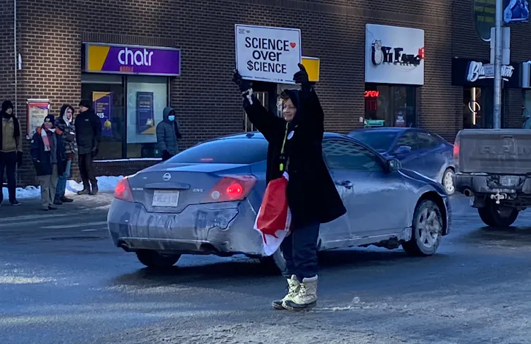 A protestor holds up a placard reading