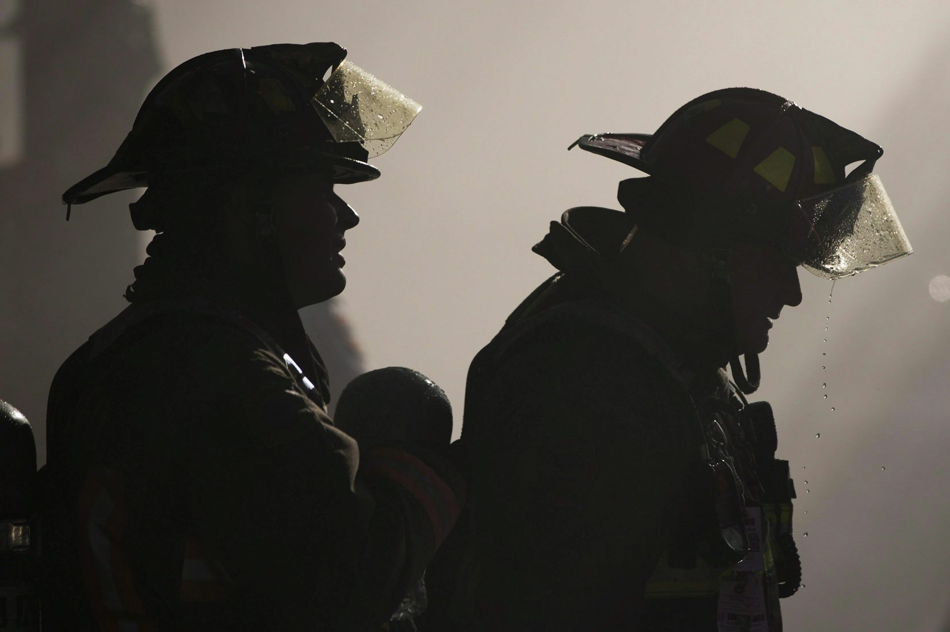 Two firefighters seen silhouetted against a smoky background