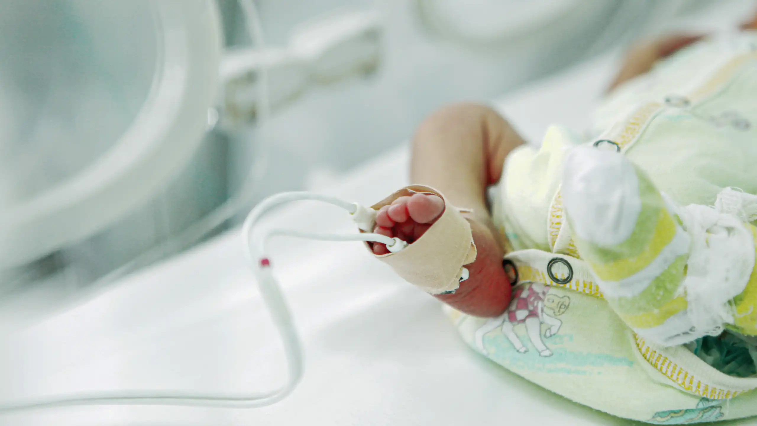 Leg and foot of tiny diapered infant lying in an incubator