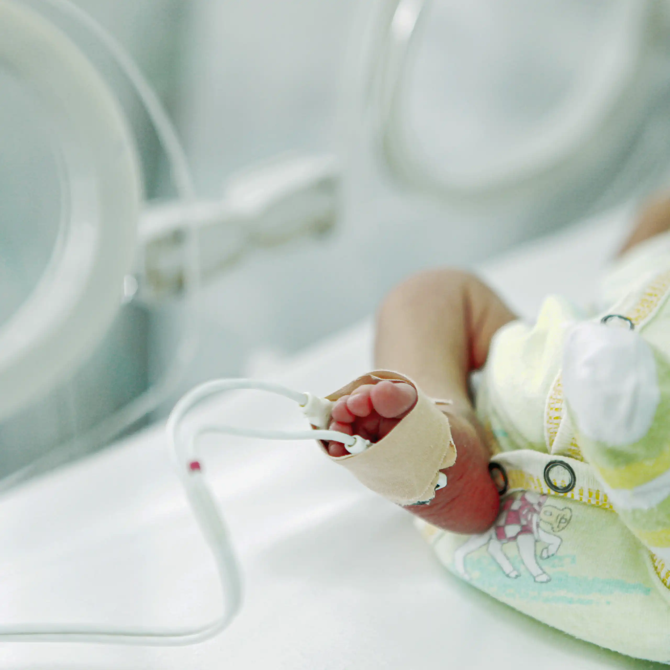 Leg and foot of tiny diapered infant lying in an incubator