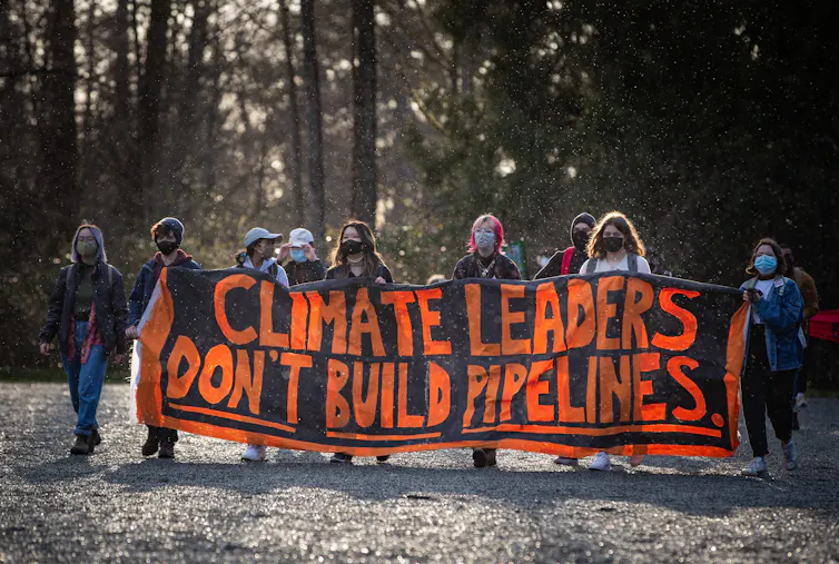 Protesters hold up a banner that says 'Climate leaders don't build pipelines'