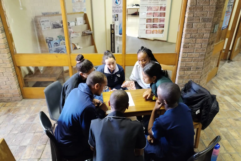 A group of young adults in discussion around a table
