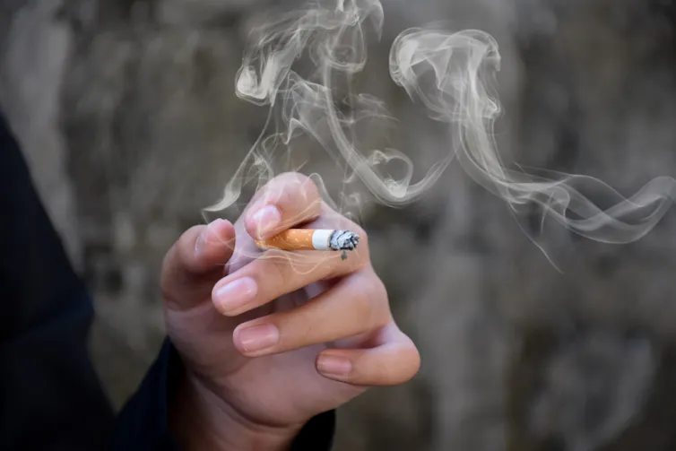 A hand holding a lit cigarette.