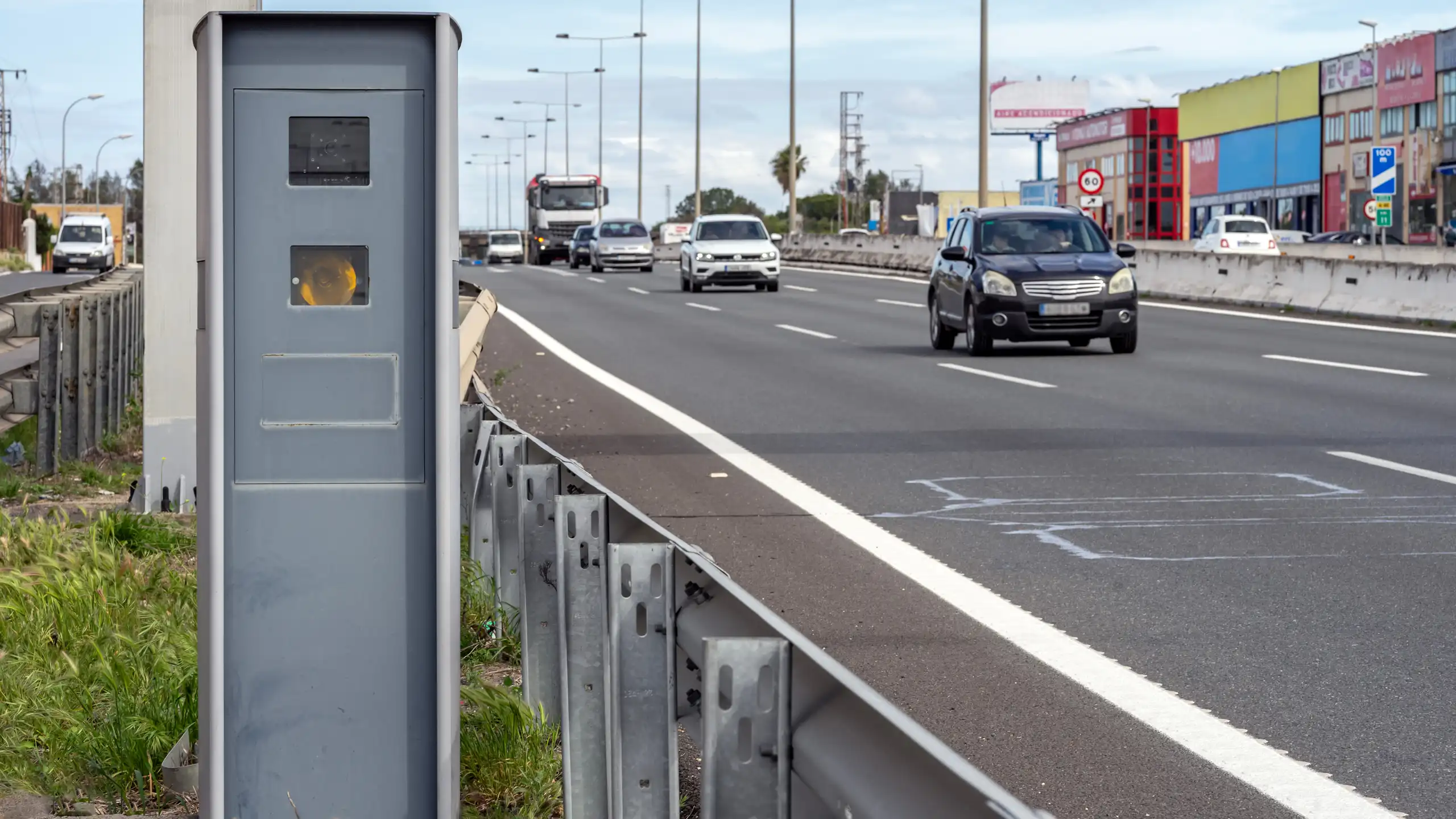 Un radar de velocitat al costat d'una carretera de tres carrils amb trànsit circulant