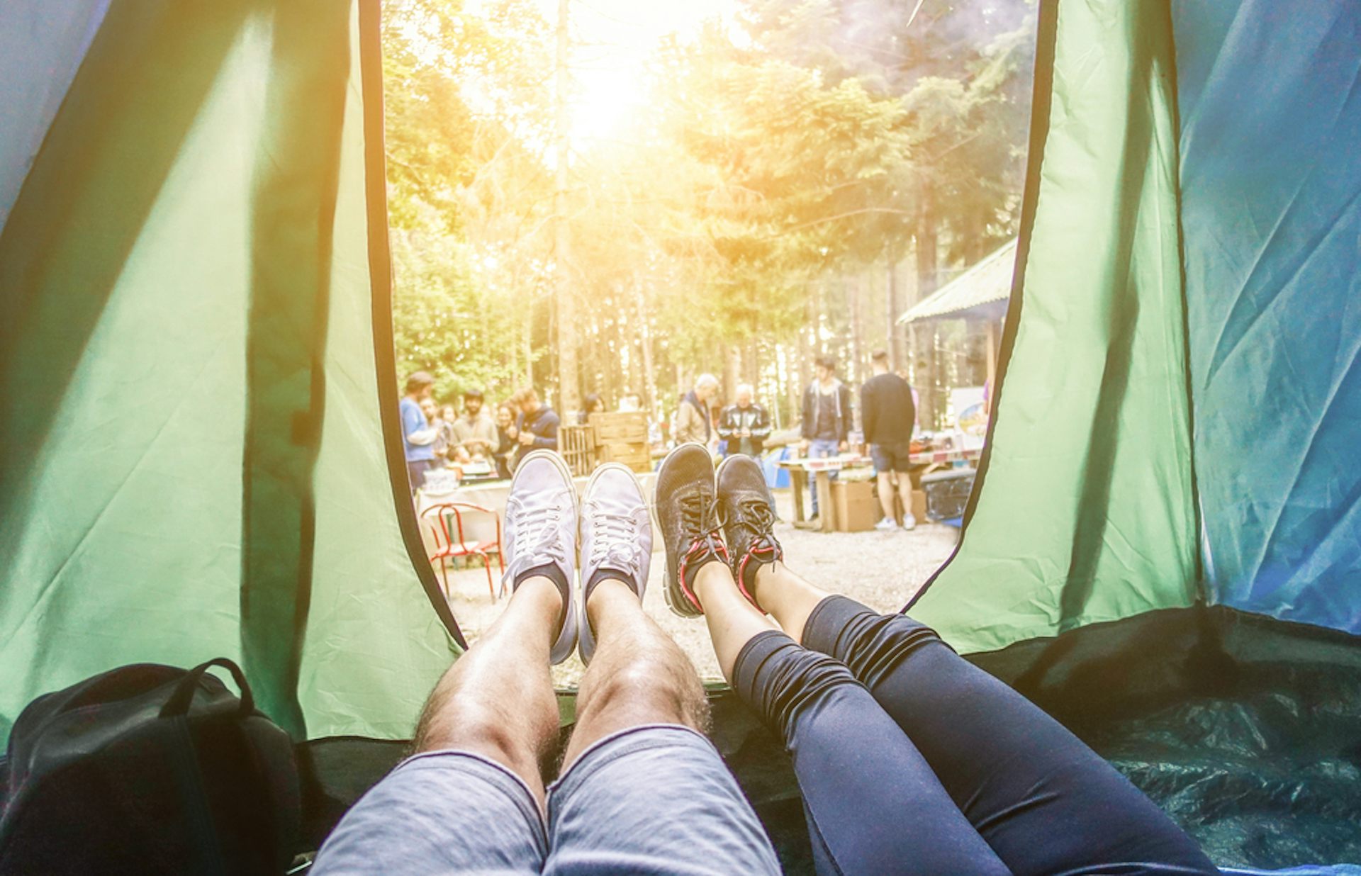Un couple dans une tente regarde l'extérieur du camping.