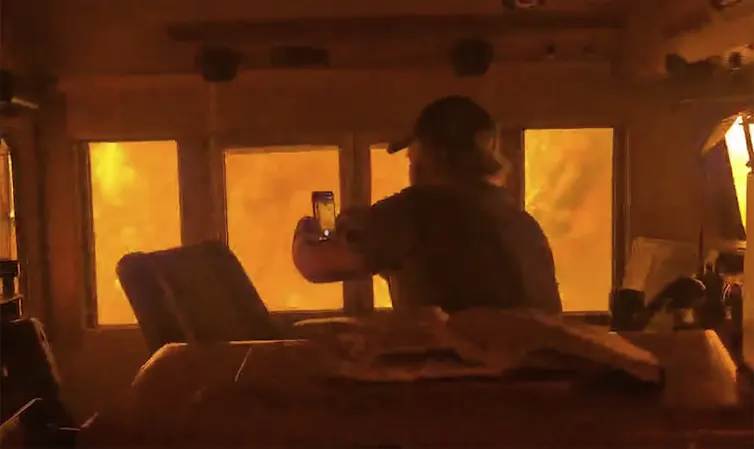Un hombre en la cabina de un tren está rodeado de llamas mientras sostiene un teléfono.