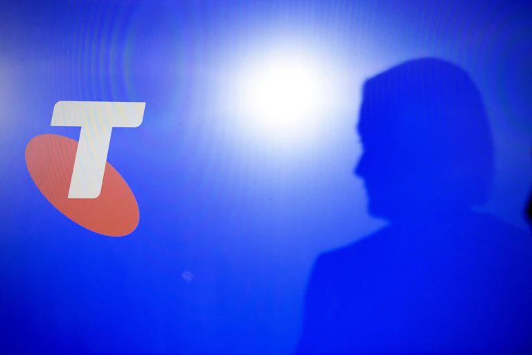 A woman's silhouette and the orange and white Telstra logo on a blue screen.