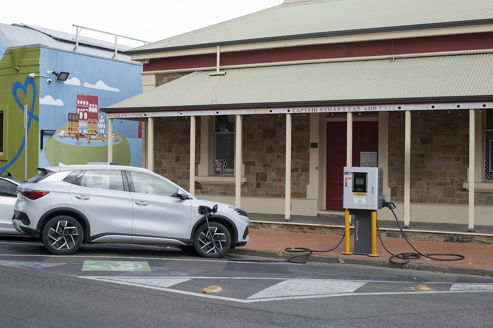 Electric car charging outside shop on a road.