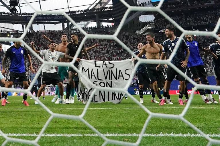Argentinian players hold up a banner reading 'Las Malvinas son Argentinas' (the Falkland Islands are Argentinian) as they celebrate their semi-final victory over England in the 2026 football World Cup