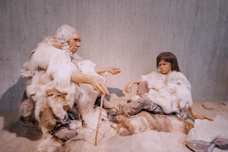 Models of neanderthal teaching her granddaughter.